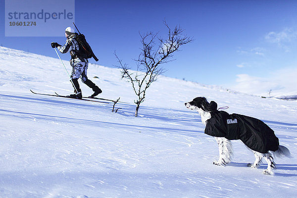 Jäger beim Skifahren mit Hund