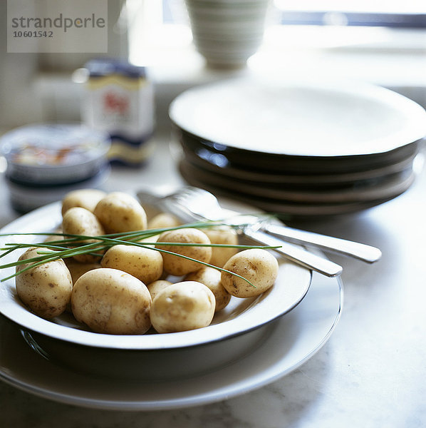 Frische Kartoffeln und Schnittlauch auf einem Teller.