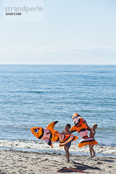 Jungen am Strand mit aufblasbarem Spielzeug