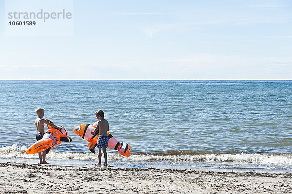 Jungen am Strand mit aufblasbarem Spielzeug