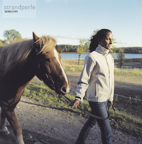 Eine Frau  die mit einem Pferd spazieren geht.
