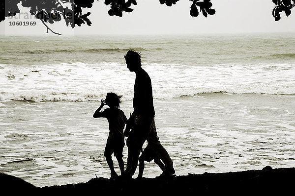 Silhouette von Vater und Sohn beim Spaziergang am Strand
