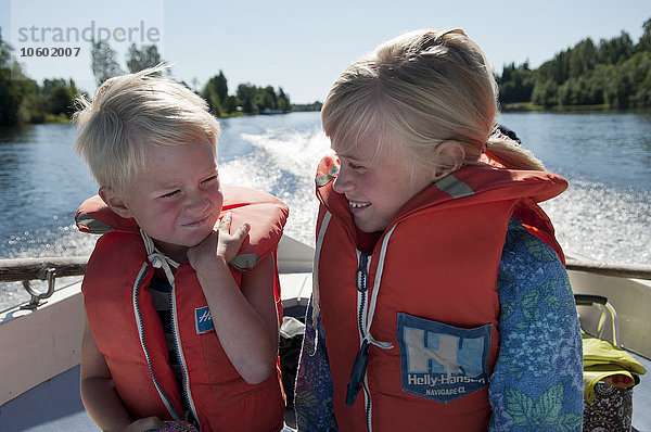 Junge und Mädchen mit Schwimmwesten auf einem Boot