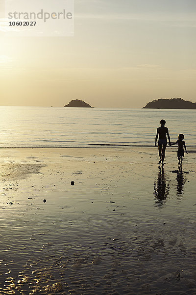 Mutter mit Sohn spazieren am Strand in der Abenddämmerung