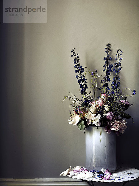 Blumen in Vase gegen graue Wand
