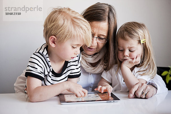 Großmutter mit Enkelkindern  die ein digitales Tablet benutzen