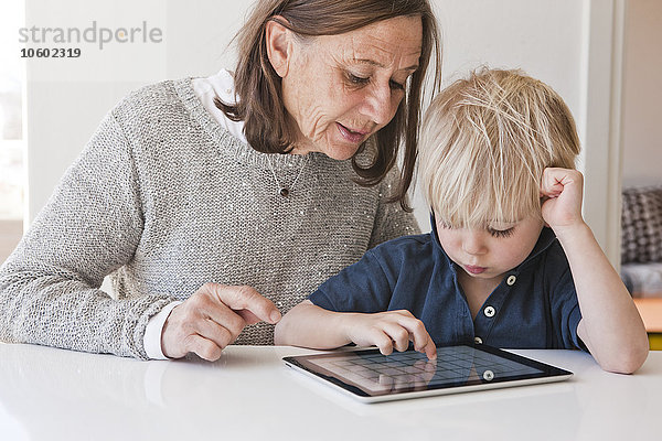 Großmutter mit Enkel  der ein digitales Tablet benutzt