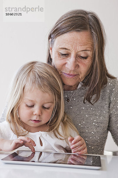 Großmutter mit Enkelin  die ein digitales Tablet benutzt