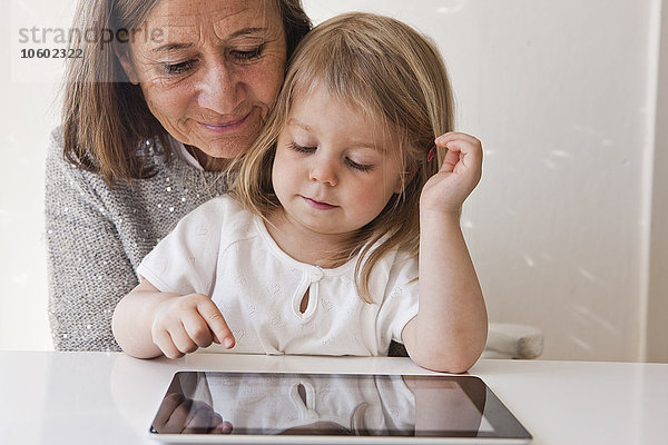 Großmutter mit Enkelin  die ein digitales Tablet benutzt