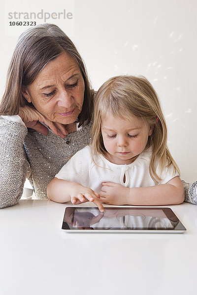 Großmutter mit Enkelin  die ein digitales Tablet benutzt