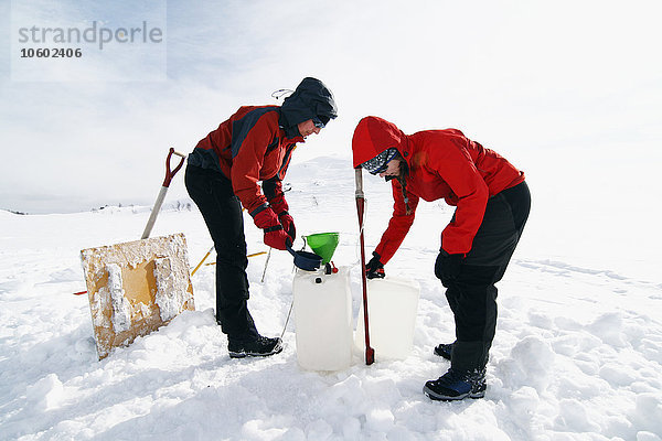 Frauen nehmen Wasser aus einem zugefrorenen See  Ammarnas  Lappland  Schweden
