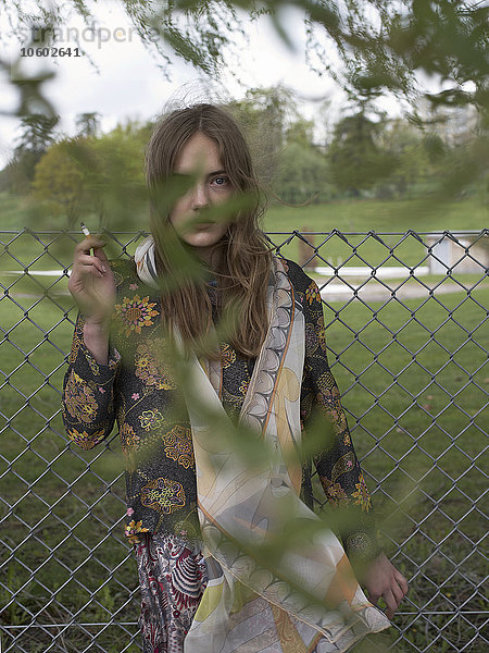 Junge Frau am Zaun beim Rauchen  Stockholm  Schweden