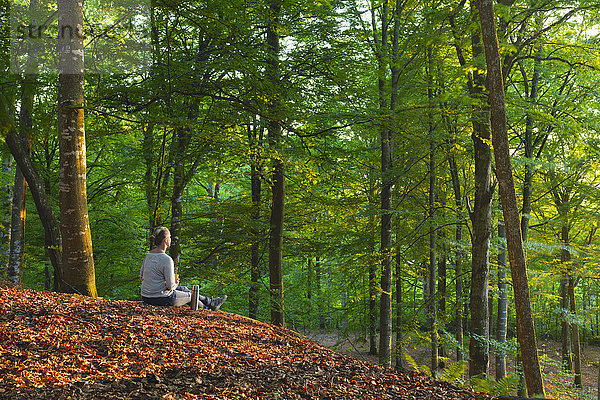 Frau sitzend im Wald