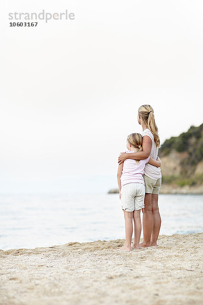 Mutter mit Tochter am Strand stehend