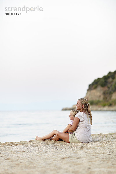 Mutter mit Tochter am Strand sitzend