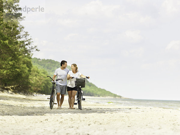 Ehepaar mit Fahrrädern am Strand