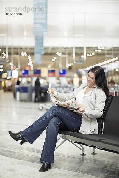 Junge Frau liest Zeitung am Flughafen