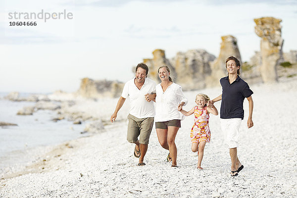 Glückliche Familie beim Laufen am Strand