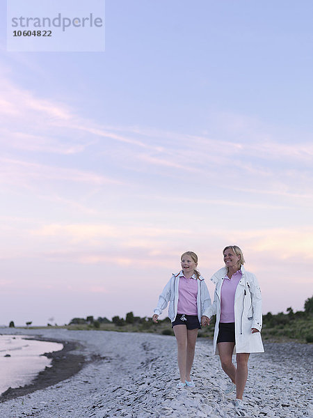 Mutter mit Tochter spazieren am Strand