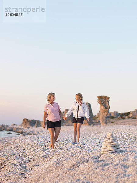 Mutter mit Tochter spazieren am Strand