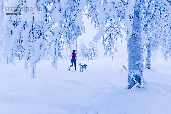 Frau läuft mit Hund im Winter