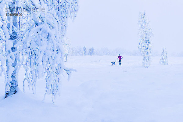 Frau läuft mit Hund im Winter