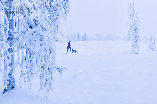 Frau läuft mit Hund im Winter