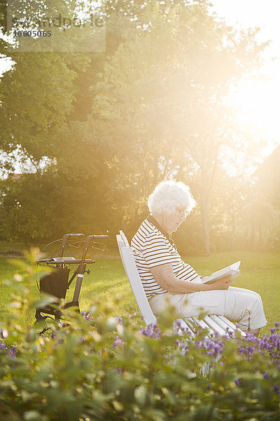 Ältere Frau liest ein Buch im Garten