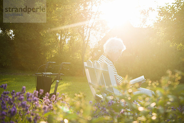 Ältere Frau liest ein Buch im Garten