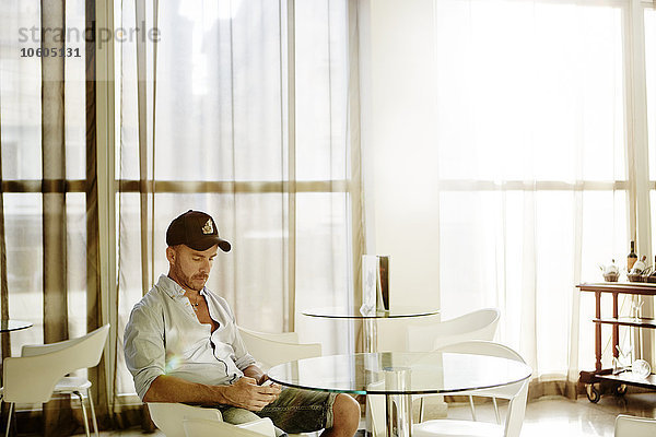 Mann mit Mobiltelefon im Café sitzend