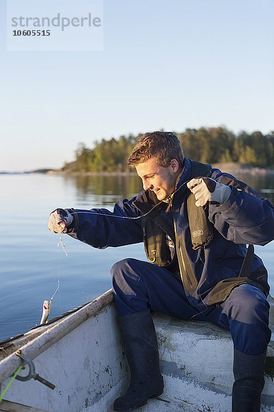 Junger Mann beim Fischen auf einem Boot
