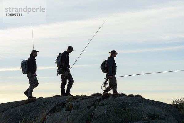 Männer mit Angelruten an der Küste
