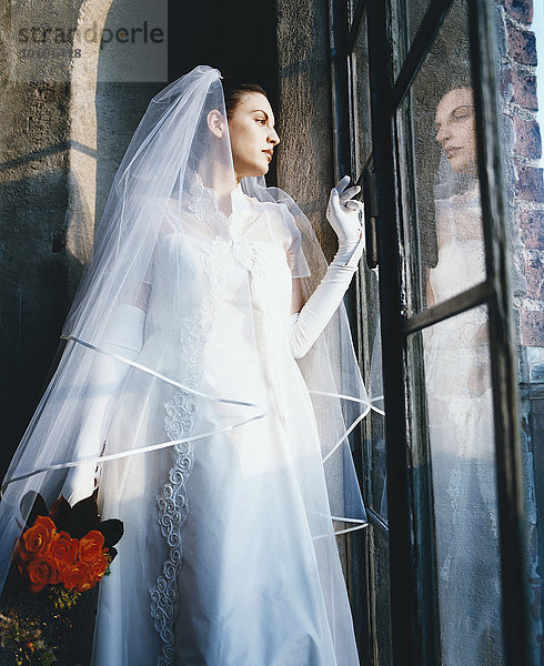Nahaufnahme der Braut  die aus dem Fenster schaut.