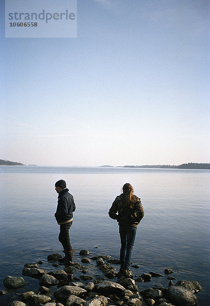 Zwei Teenager stehen auf Felsen am Meer  Vagnharad  Schweden.