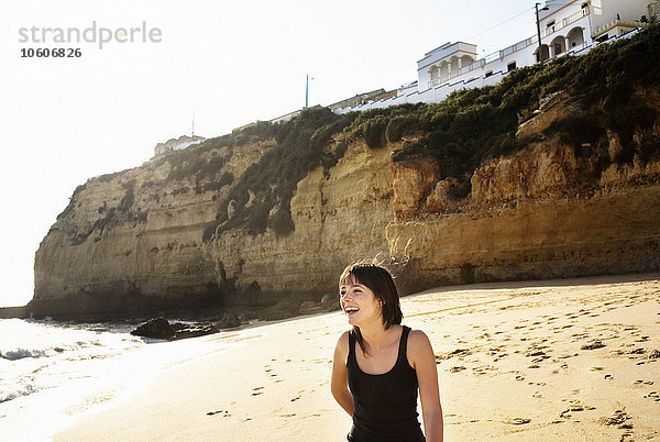 Eine junge lächelnde Frau am Strand  Portugal.