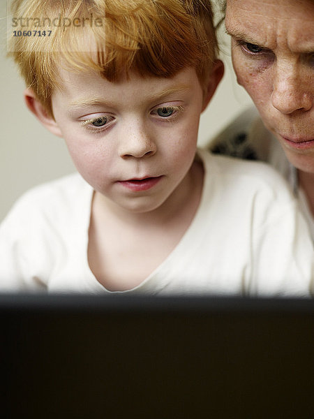Ein Junge und seine Mutter schauen auf einen Computer  Schweden.