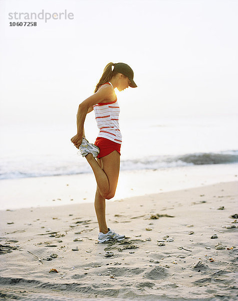 Eine Frau macht Dehnübungen an einem Strand.