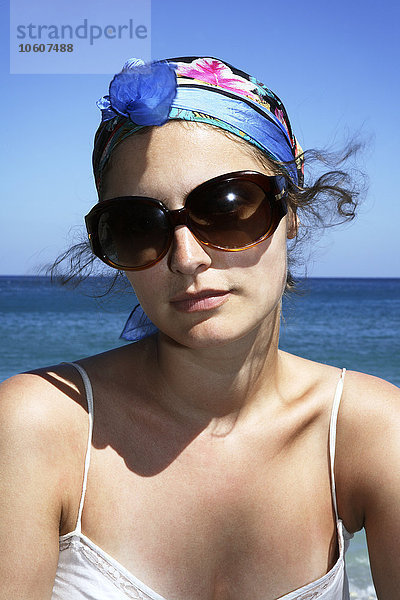 Junge Frau mit Sonnenbrille am Meer sitzend  Griechenland.