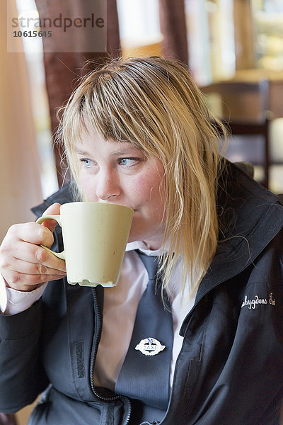 Frau trinkt aus einer Tasse in einem Cafe