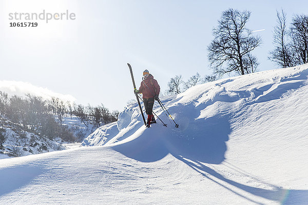 Mann mit Skiern auf verschneiter Piste stehend