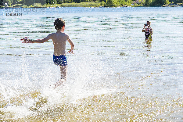 Junge läuft im Wasser  Mutter fotografiert