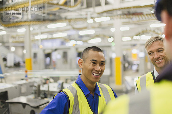 Arbeiter in reflektierender Kleidung sprechen in der Fabrik