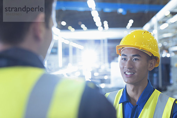 Arbeiter in reflektierender Kleidung sprechen in der Fabrik