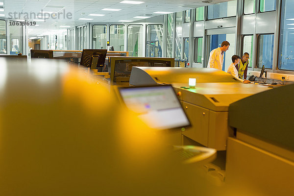 Mitarbeiter am Computer hinter den Druckern in der Druckerei
