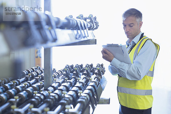 Ingenieur mit Zwischenablage zur Kontrolle des Förderbandes einer Druckmaschine