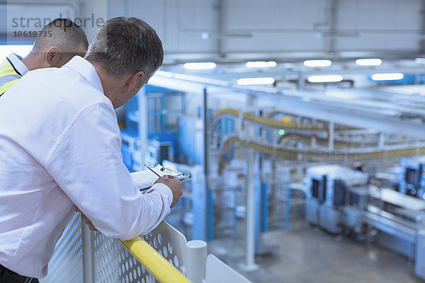 Arbeiter am Geländer mit Blick auf die Fabrik