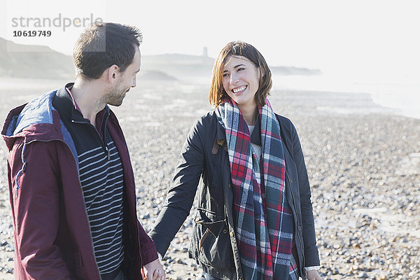 Lächelndes Paar beim Spaziergang am Strand