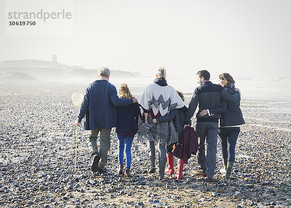 Mehrgenerationen-Familienwandern in einer Reihe am Strand