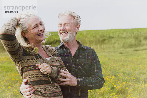 Lächelndes Seniorenpaar umarmt sich im Feld