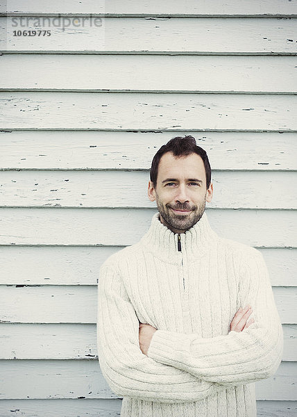 Portrait brünetter Mann im Pullover mit gekreuzten Armen